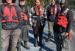 Johnny Amos (far right) manages Creative Salmon’s Baxter Islet farm site in Tofino Inlet in Tla-o-quiaht traditional territory. Johnny, along with all his crew, live in the nearby Tla-o-qui-aht community of Ty-histanis. From left: Isiah David, Donovan Hayes, Sean Hayes, and Connor Yellowbird. (Coalition of First Nations for Finfish Stewardship photo)