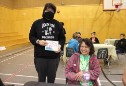 Harvey Tate, Grade 10, presents a copy of the book to elder Maisie Marshall, residential school survivor.