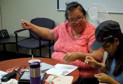 Lisa Watts, a MMIWG family support worker with the Nuu-chah-nulth Tribal Council, works on red dress pins for a billboard fundraising project. (Karly Blats photo)