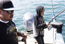 Matthew Jack guides his daughter, Norah, as she reels in a fish while fishing close to their home in Kyuquot.