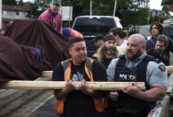 Joshua Charleson (centre) helps to lift the totem pole onto a barge to be transported to the Tla-o-qui-aht village of Opitsaht, on Meares Island, on June 29, 2022.