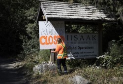 Jessie Masso hangs a road closure sign at the entrance of West Main Forest Service Road, near Tofino, on August 10, 2021. 