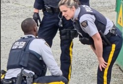 A third officer soon comes into view, who puts on latex gloves and picks up some things from under the restrained man, including something inside a Ziplock bag. (Facebook video still)