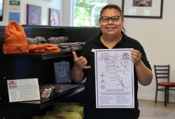 Tsawaak RV Resort and Campground front desk administrator Gina Coon throws a shaka and shows off the Rising Tide surf map poster, which are on sale for $10 at the Tsawaak surf shop and gallery.