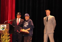 Valedictorian Stephen Mack Jr. stands at the podium with his grandfather Steve Lucas Sr. by his side, as Principal Nick Seredick watches.