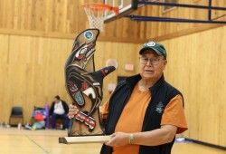 Nuu-chah-nulth carver Vince Smith holds the wood trophy that depicts the Charleson family crest of an orca transforming into a wolf.