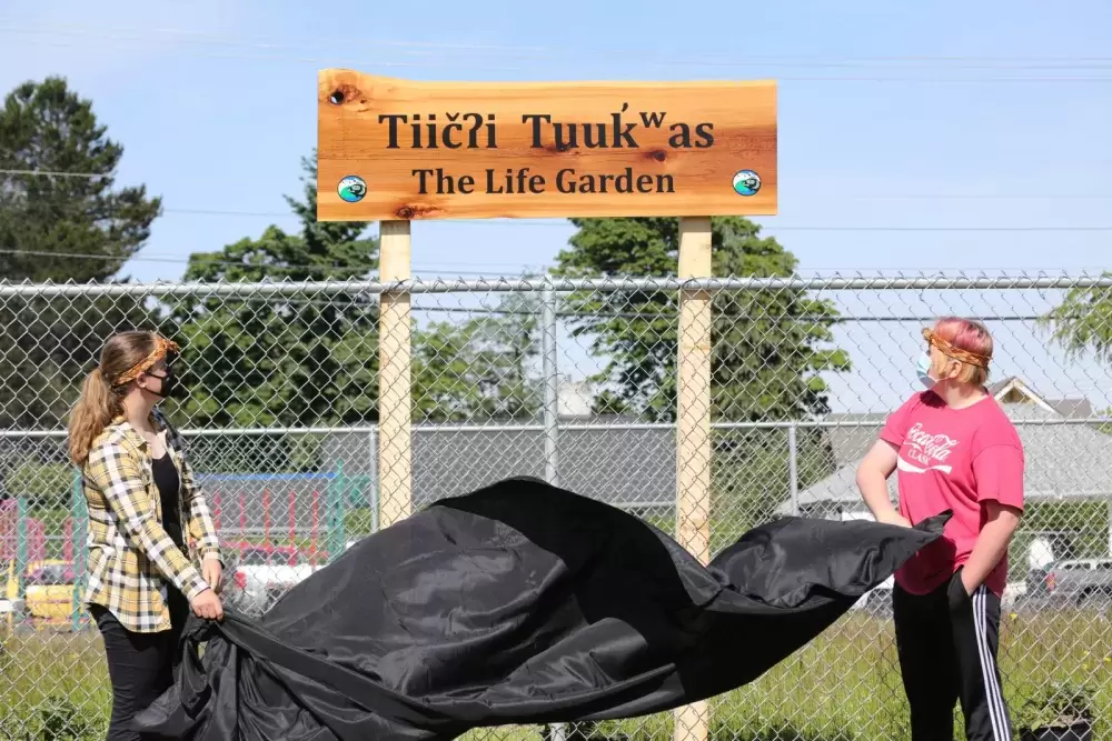 Grade 9 students Gabriella Stanley (left) and Riley Swanson unveil the name for the Eighth Avenue Learning Centre's new garden on June 17.