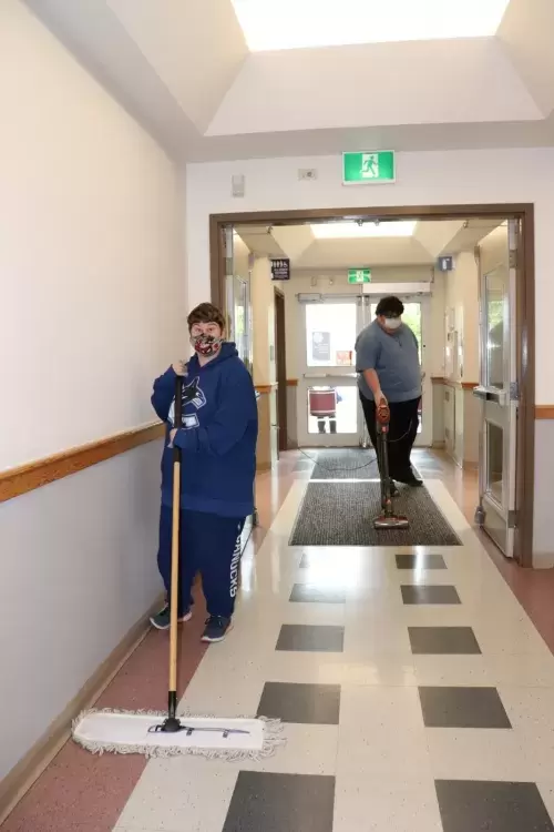 Jenna Domovich and Josh Watson clean a floor at the North Island College campus in Port Alberni.