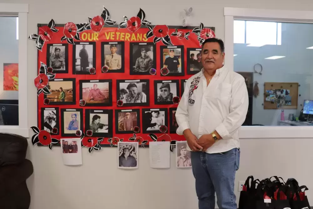 Dave Jacobson, Usma Elder's Coordinator poses with collection of war veteran photos