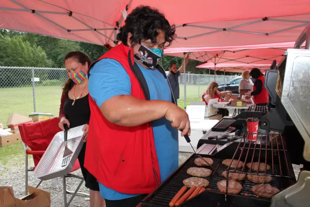 Teechuktl employee Lee Lucas works the barbeque as other staff prepare lunches to be picked up at Dry Creek Park on June 15. (Eric Plummer photo)