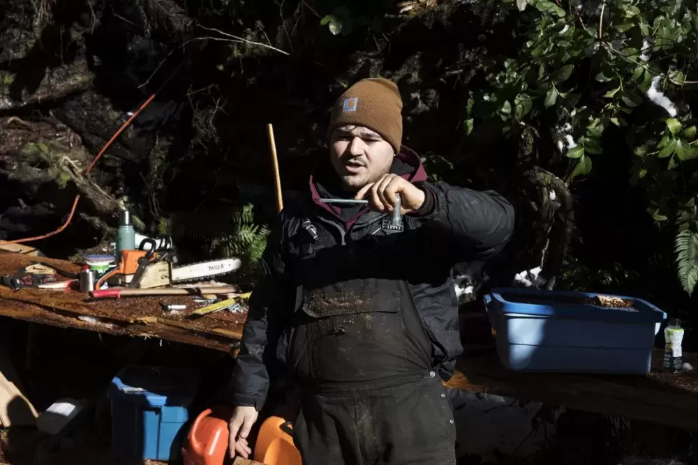 Joshua Watts measures how much more needs to be cut out of the hull of the canoe, on Feb. 16, 2021. 