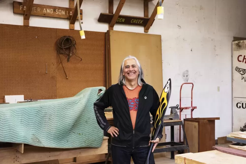 Rodney Sayers, a Nuu-chah-nulth artist from the Hupačasath First Nation, poses with a sample of his work in his Port Alberni studio on Oct. 4. (Melissa Renwick photo)