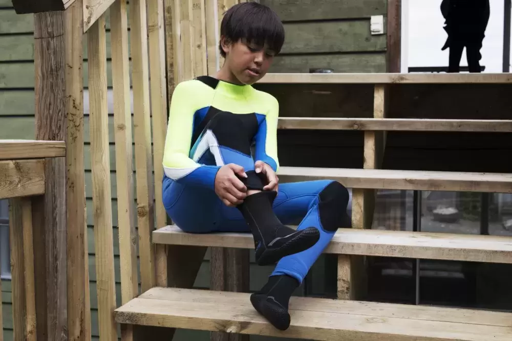 Nathan Atleo, 11, boots surf boots on in Esowista before the youth surf club, in Tofino, on June 14, 2021.