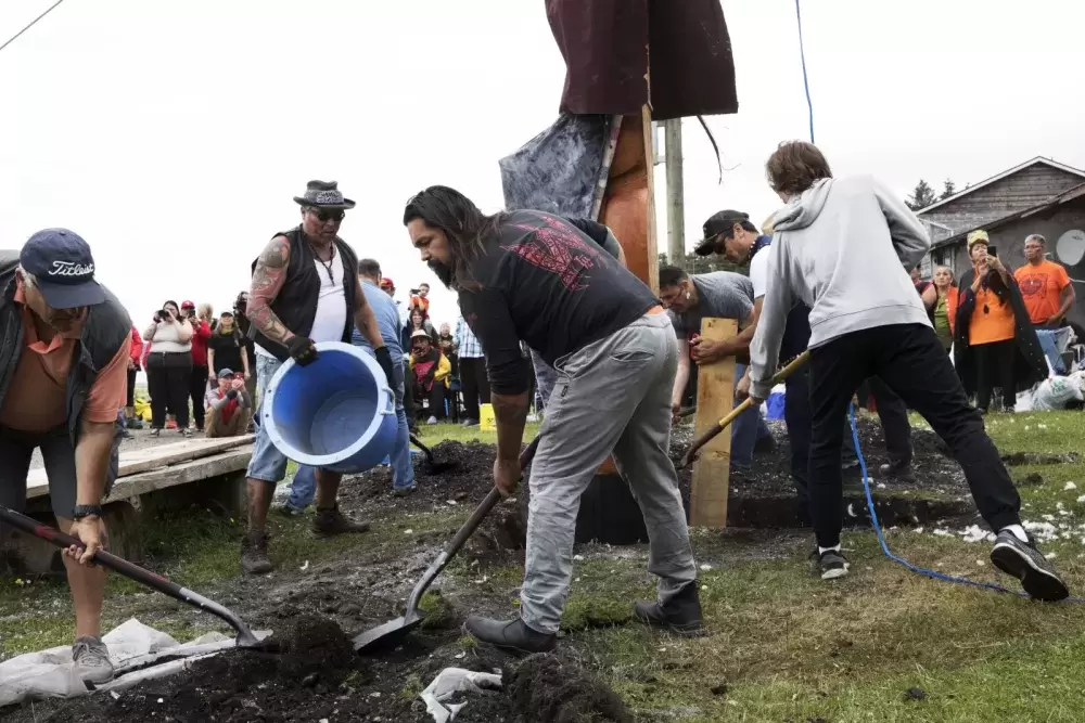 After the totem pole was raised, men raced to fill the hole in which it sat with soil, in Opitsaht, on Meares Island, on July 1, 2022.