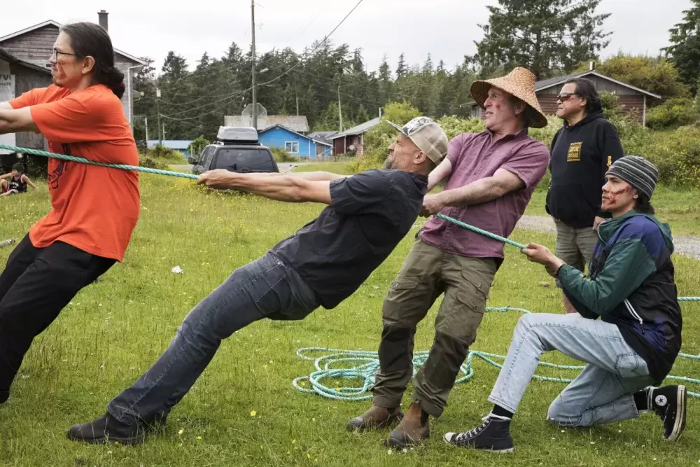 Men pull on a rope behind the totem pole so that it doesnÕt fall forward which soil is packed around it, in Opitsaht, on Meares Island, on July 1, 2022.