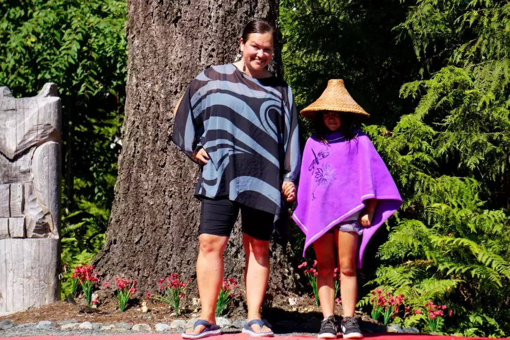 Naomi Nicholson and a young helper model Indigenous-made clothing from Nicholson’s personal collection at Cims Fest on Aug. 6.