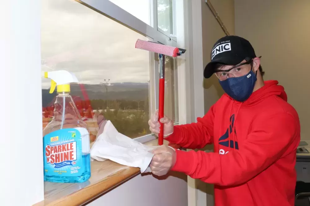 Myles Bernard cleans a window at the North Island College campus in Port Alberni.