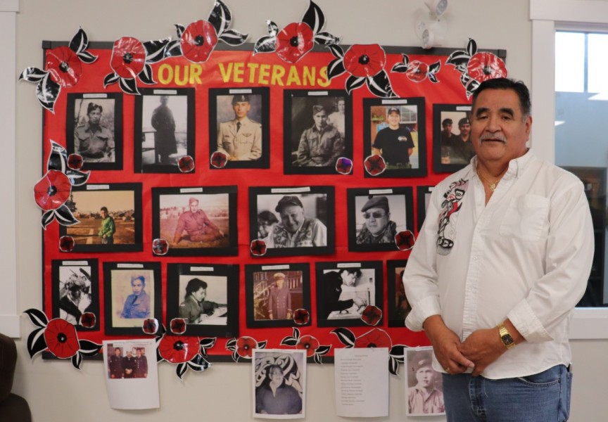 Dave Jacobson, Usma Elder's Coordinator poses with collection of war veteran photos