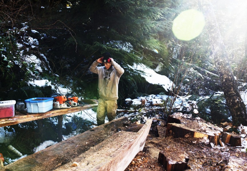 Ryan Sabbas helps Joe Martin carve a canoe for Valeen Jules within Tla-o-qui-aht First Nation traditional territory off the Pacific Rim Highway, on Feb. 16, 2021. 