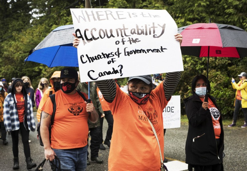 Residential school survivor Alice George holds up a sign while marching through the streets of Tofino to honour the survivors and victims of the residential school system on the first National Day for Truth and Reconciliation, on September 30, 2021.