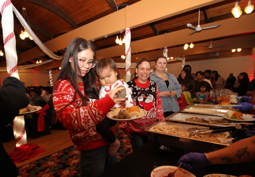 Ciara Joseph holds Savannah Joseph-Frank, gathering a plate of food with Jolen Joe and Saphiah Lauder at Port Alberni's Italian Hall on Dec. 10.