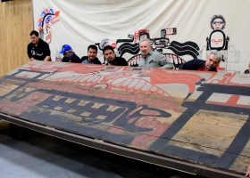 Huu-ay-aht men lift the wooden screen into place