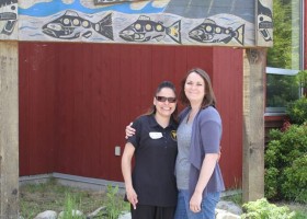 Jolene Joe, teaching assistant, K to 2, and teacher Eva Clarke, K to 2 in front of school sign.