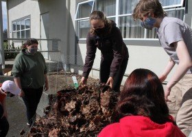 Gabriella Stanley (centre) Gracie Martinez (left), Julian Larrivee-Woods and other students in the Grade 8-9 class move leaves that have been composting by the Eighth Avenue Learning Centre over the winter.