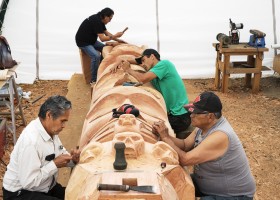 (From left to right) Joe Martin, Patrick Amos, Robin Rorick and Robert Martin (Nookmis) carve a totem pole inside a tent set up at the Tofino Botanical Gardens, on July 9, 2021.